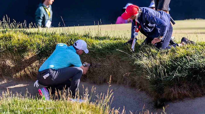 Rory McIlroy and a USGA rules official examine an embedded ball situation at the 2023 U.S. Open.
